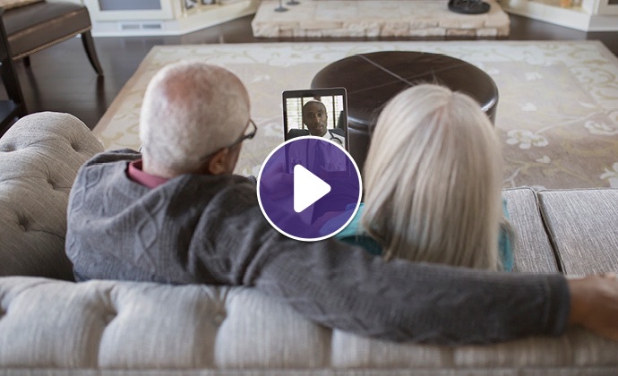 An older couple talks with a physician via iPad from their sofa at home